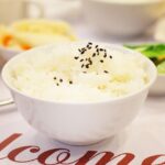 Piatti di riso bianco con un misuratore di glicemia vicino, evidenziando il suo impatto sulla salute.