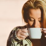 Tazza di caffè con chicchi, simbolo del legame tra consumo di caffè e vitamina D.