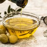 Bottiglia di olio extravergine d'oliva su tavolo, simbolo di salute cardiovascolare.