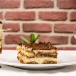 Tiramisù con crema al mascarpone, strati di savoiardi e cacao in polvere, decorato elegantemente.