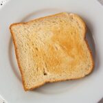 Fette biscottate in primo piano con etichette che evidenziano sostanze dannose per la salute.