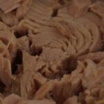 Immagine di una lattina di tonno con etichetta di marca controversa, evidenziata come scadente.