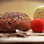 Fette di pane integrale su un tavolo, con burro e marmellata, simbolo di una colazione sana e nutriente.